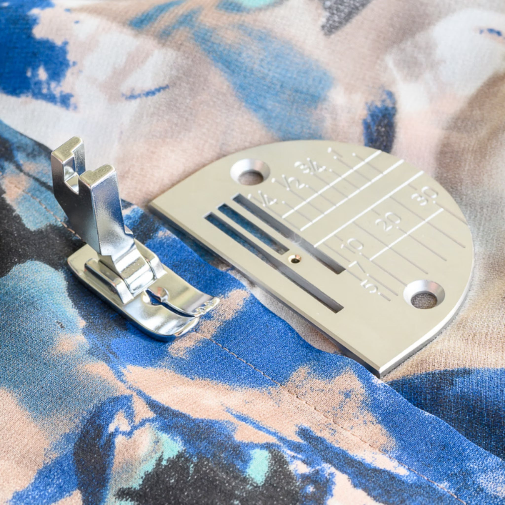 Metal sewing machine foot on a colorful fabric background